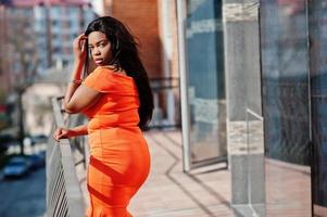 afroamerikanerfrau modell xxl im orangefarbenen kleid. foto