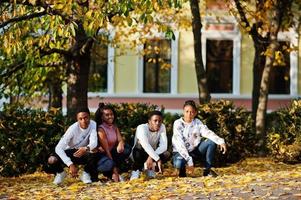 Vier afrikanische Freunde, die am sonnigen Herbsttag durch die Straßen einer antiken Stadt gehen. foto