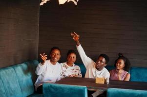 glückliche afrikanische freunde sitzen und plaudern im café. gruppe schwarzer menschen, die sich im restaurant treffen und kellner anrufen. foto