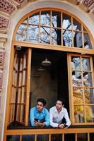 Zwei südasiatische Männer posierten bei einem Geschäftstreffen im Café. inder arbeiten mit verschiedenen geräten zusammen und unterhalten sich. Mobiltelefone halten. foto