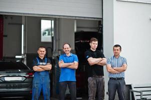 Thema Autoreparatur und -wartung. drei Mechaniker und Manager in Uniform im Autoservice. foto