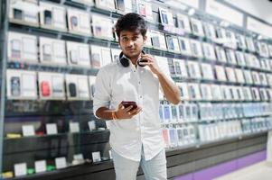 inder kundenkäufer im handyladen mit drahtlosen kopfhörern verbinden sich mit seinem smartphone. Konzept der südasiatischen Völker und Technologien. handy shop. foto