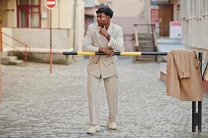 stylischer Afro-Mann im beigen Old-School-Anzug. Modischer junger afrikanischer Mann in Freizeitjacke auf nacktem Oberkörper. foto