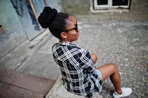 Hip-Hop-Afroamerikanermädchen auf Sonnenbrillen und Jeans-Shorts. Lässiges Straßenmodeporträt einer schwarzen Frau. foto