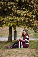 Porträt eines jungen schönen indischen oder südasiatischen Teenager-Mädchens im Kleid, das im Herbstpark posiert. foto