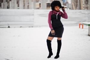 Afroamerikanerin mit lockigem Haar und Handschuhen, die am Wintertag gestellt wurden. foto