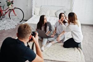 Maskenbildner bereiten vor dem Fotoshooting zwei Zwillingsmodelle mit Laptop im Studio vor. Fotograf schießen. Teamarbeit zusammen. foto