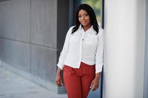 formell gekleidete afroamerikanische Geschäftsfrau in weißer Bluse und roter Hose. erfolgreiche dunkelhäutige Geschäftsfrau. foto