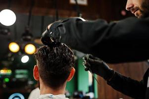 hübscher bärtiger mann im friseursalon, friseur bei der arbeit. foto