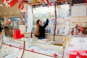 Porträt des jungen kaukasischen weiblichen Verkäufers. kleines Geschäft mit Süßigkeiten-Souvenir-Shop. foto