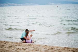 Sommerferien. eltern und menschen outdoor-aktivitäten mit kindern. schöne Familienferien. vater, schwangere mutter, kleine tochter am seesandstrand. foto