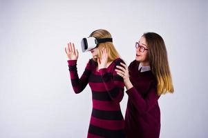 Zwei Mädchen in lila Kleidern probieren im Studio eine Virtual-Reality-Brille aus. foto