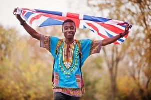 afrikanischer mann in afrika traditionelles hemd auf herbstpark mit großbritannien-flagge. foto