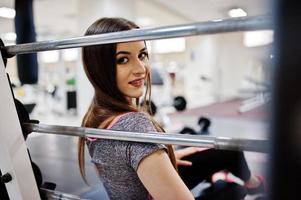 junges brünettes sexy schlankes mädchen, das im fitnessstudio trainiert. foto