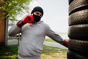 porträt trägt einen arabischen boxermann in schwarzer medizinischer gesichtsmaske, der während der coronavirus-quarantäne im freien boxt. foto