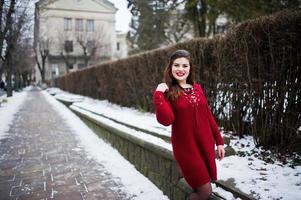 Brünette plus Größenmodell bei Rot auf der Straße der Stadt. foto