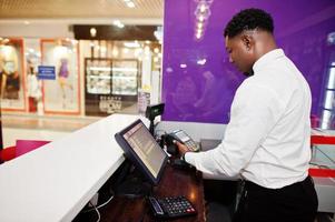 Der afroamerikanische Barkeeper an der Bar verwendet ein Kreditkartenterminal an der Kasse. foto