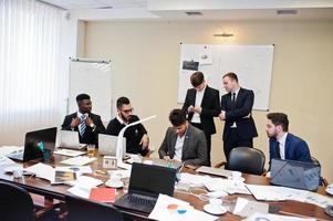 sechs gemischtrassige Geschäftsleute im Büro am Tisch. diverse gruppe männlicher angestellter in formeller kleidung diskutieren. foto