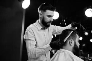 hübscher bärtiger mann im friseursalon, friseur bei der arbeit. foto