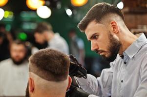 hübscher bärtiger mann im friseursalon, friseur bei der arbeit. Nacken schließen. foto