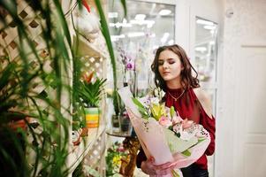 Brünettes Mädchen in Rot kauft Blumen im Blumenladen. foto