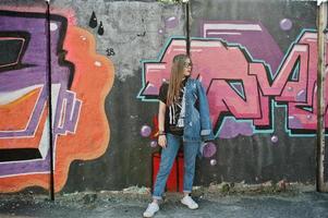 stylisches, lässiges Hipster-Mädchen in Jeans und Brille gegen große Graffiti-Wand. foto