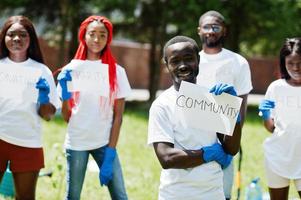 eine gruppe glücklicher afrikanischer freiwilliger hält ein leeres brett mit gemeinschaftsschild im park. afrika-freiwilligenarbeit, wohltätigkeit, menschen und ökologiekonzept. foto