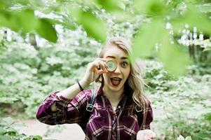 Porträt eines attraktiven blonden Mädchens, das mit einem Kompass in einem Wald posiert. foto