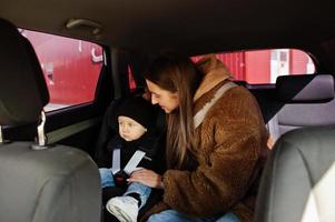 junge Mutter und Kind im Auto. Kindersitz auf Stuhl. Fahrsicherheitskonzept. foto