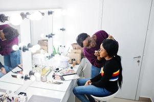 Afroamerikanerin beim Schminken durch Make-up-Künstlerin im Schönheitssalon. foto