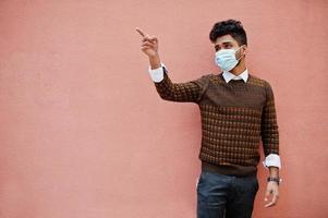 Coronavirus Covid-19-Konzept. südasiatischer indischer mann mit maske zum schutz vor koronavirus isoliert auf rosa hintergrund. foto