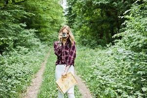 Porträt eines wunderschönen jungen Mädchens im Tartanhemd, das mit der Kamera im Wald fotografiert. foto