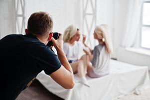 Mann Fotograf schießt im Studio zwei Mädchen, während sie ihre eigene Maskencreme herstellen. professioneller fotograf bei der arbeit. foto