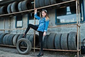 Junges Hipster-Mädchen in Jeansjacke und Kopftuch in der Reifenmontagezone. foto