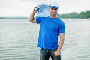 Lieferbote mit Wasserflasche auf der Schulter. foto