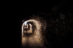 dunkler, vernarbter Tunnel mit ein paar Lichtern unter der Burg. foto