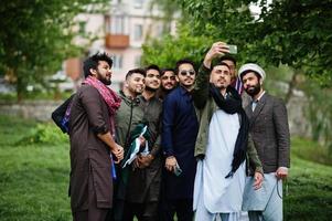 Gruppe pakistanischer Männer, die traditionelle Kleidung tragen, Salwar Kameez oder Kurta, die Selfie auf dem Handy machen. foto