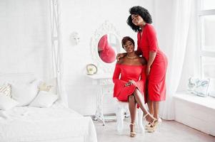 zwei afroamerikanische modemodelle in rotem schönheitskleid, sexy frau, die abendkleid im weißen vintage-raum posiert. foto