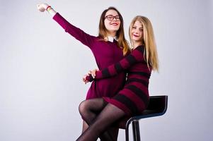 Mädchen in lila Kleidern haben Spaß und posieren auf dem Stuhl im Studio. foto