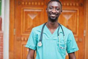 Porträt eines afrikanischen männlichen Arztes mit Stethoskop im grünen Mantel. foto