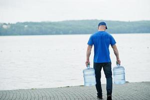 Rückseite des Zustellers mit Wasserflaschen an den Händen. foto