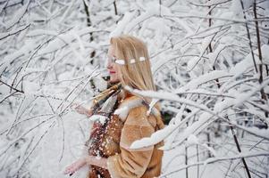 Porträt eines blonden Mädchens mit Brille, rotem Pelzmantel und Schal am Wintertag. foto