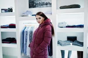 Brünettes wunderschönes Mädchen in der Bekleidungsgeschäft-Boutique bei Winterjacke. foto