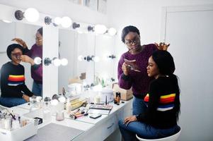 Afroamerikanerin beim Schminken durch Make-up-Künstlerin im Schönheitssalon. foto