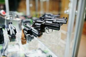 Verschiedene Waffen und Revolver in Regalen lagern Waffen im Ladenzentrum. foto