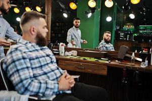 hübscher bärtiger mann im friseursalon, friseur bei der arbeit. foto