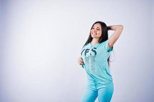 Porträt einer jungen schönen Frau in blauem oder türkisfarbenem T-Shirt und Hose, die im Studio posiert. foto