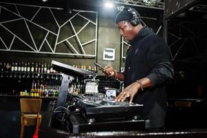 afrikanisch-amerikanischer dj spielt musik auf decks im nachtclub. foto