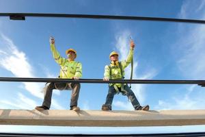 Bauarbeiter tragen Sicherheitsgurte und Sicherheitsgurte, die auf industriellen Metalldächern arbeiten. foto