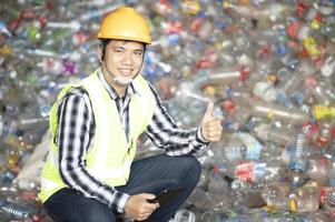 Ein Arbeiter kontrolliert das Recycling einer Recyclinganlage. Plastikflaschen und Plastikmüll foto